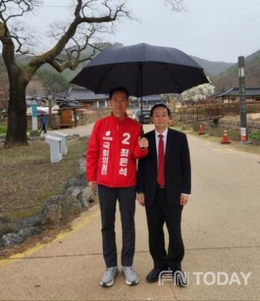 옻골마을 입구에서 최은석 후보와 최성덕 박사가 옻골 입향조 최동집 선생이 심은 회나무 앞에서 기념 촬영을 하고 있다.
